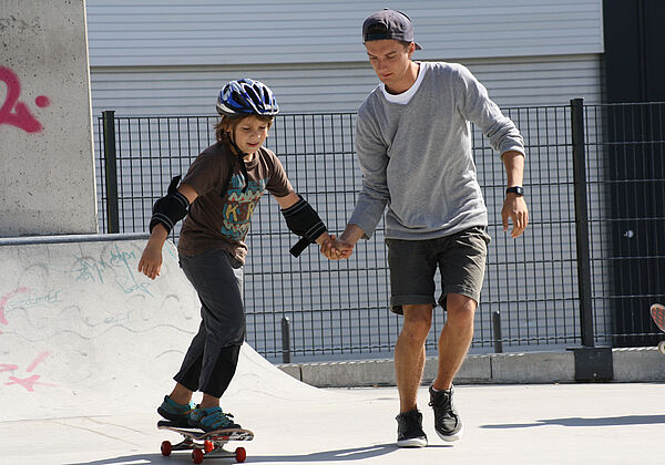 An der Hand sind die ersten Fahrversuche mit dem Skateboard einfacher.