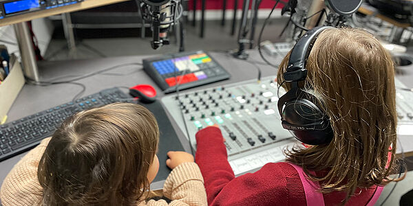 Radio Feierwerk fuer Kinder Mein Minimorgen Moderatorin Livia spricht mit einem Freund die Sendung im Studio ein