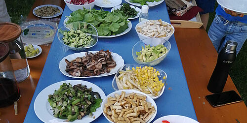 Gedeckter Tisch mit Tellern, darauf buntes Essen