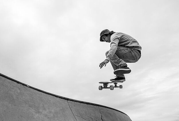 Foto Skate-Action mit Feierwerk Boom. Zu sehen ist ein Mann mitten im Sprung mit dem Skateboard.